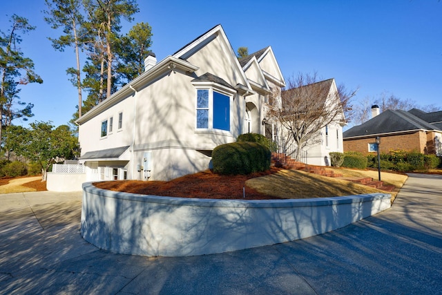 view of home's exterior with fence, a chimney, and stucco siding