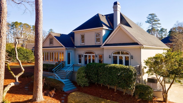 view of front of property featuring french doors, a chimney, and stucco siding