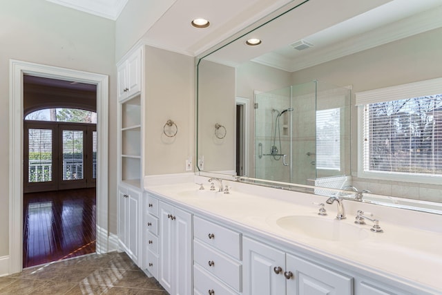 bathroom with a stall shower, a sink, and crown molding