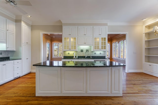 kitchen featuring glass insert cabinets, light wood-type flooring, white cabinets, and a sink