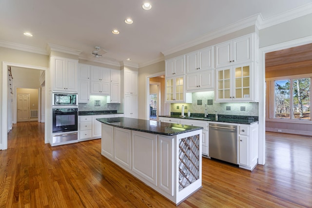 kitchen featuring glass insert cabinets, white cabinetry, a kitchen island, dark stone countertops, and black appliances