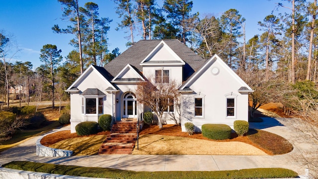 view of front facade featuring a shingled roof and stucco siding