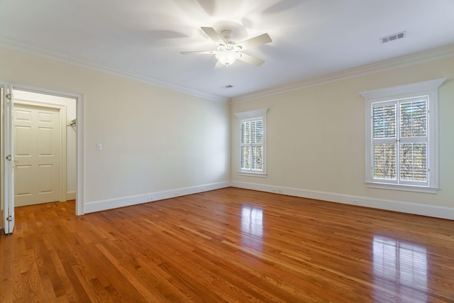 unfurnished room featuring light wood finished floors, visible vents, and ornamental molding