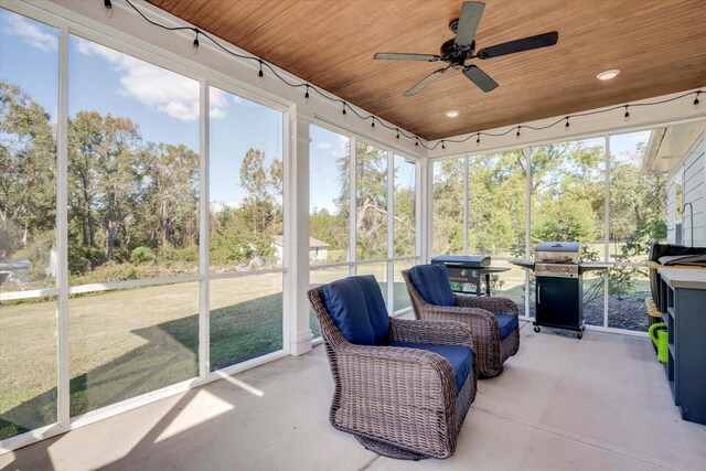 sunroom / solarium with ceiling fan, a healthy amount of sunlight, and wooden ceiling