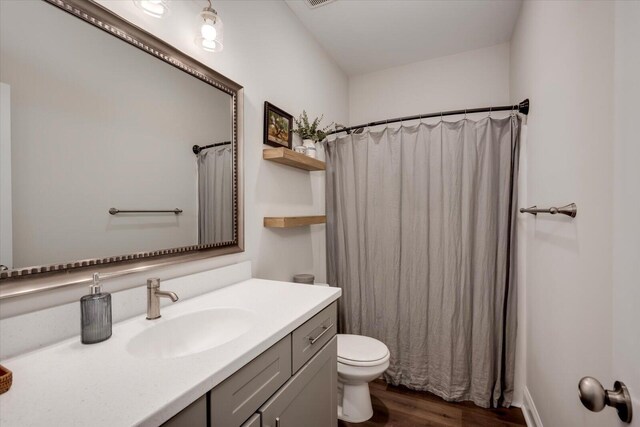 bathroom with wood-type flooring, vanity, toilet, and walk in shower