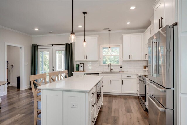 kitchen with french doors, white cabinets, sink, appliances with stainless steel finishes, and decorative light fixtures