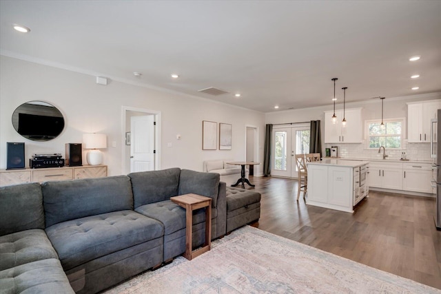 living room with crown molding, french doors, light hardwood / wood-style floors, and sink