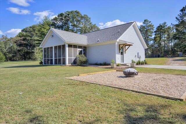 back of property with a sunroom and a yard