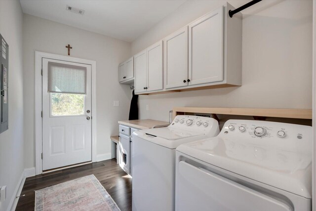 laundry area with washing machine and clothes dryer, a barn door, dark wood-type flooring, and cabinets