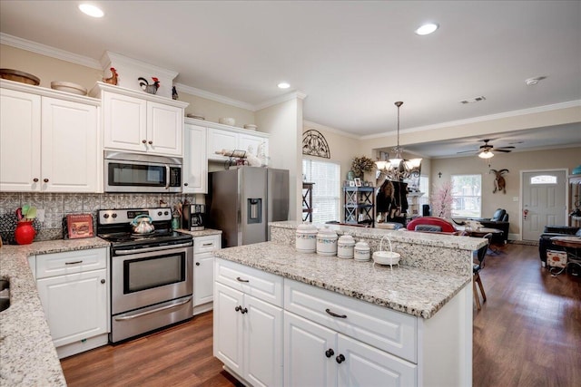 kitchen with backsplash, white cabinets, ceiling fan with notable chandelier, hanging light fixtures, and appliances with stainless steel finishes