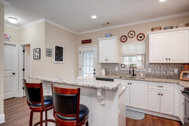 kitchen with a breakfast bar area, white cabinetry, sink, and a kitchen island