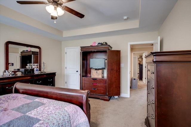 carpeted bedroom featuring a raised ceiling and ceiling fan