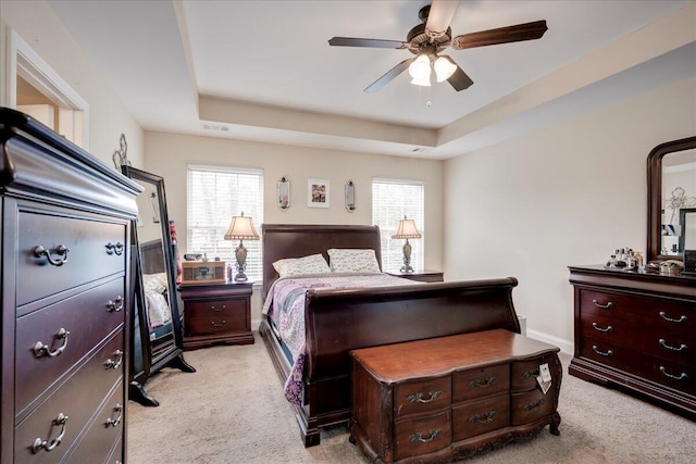 carpeted bedroom featuring ceiling fan and a tray ceiling