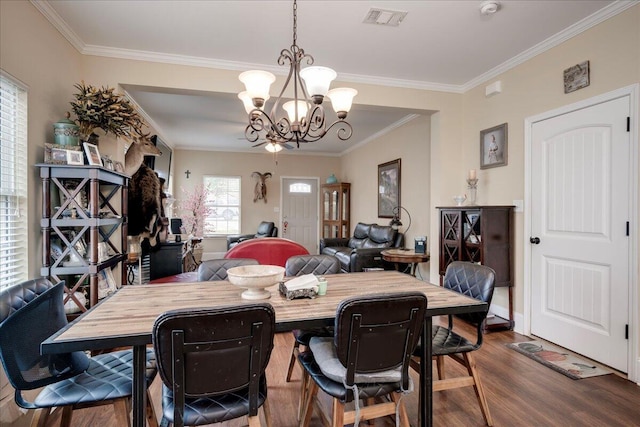 dining area with hardwood / wood-style floors, crown molding, and a notable chandelier