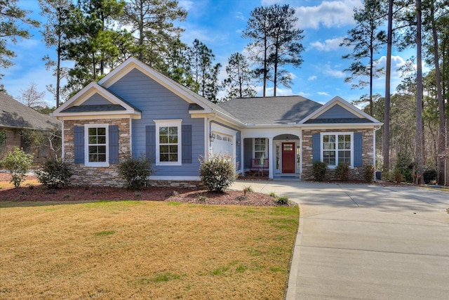 view of front of home featuring a garage, stone siding, driveway, and a front lawn