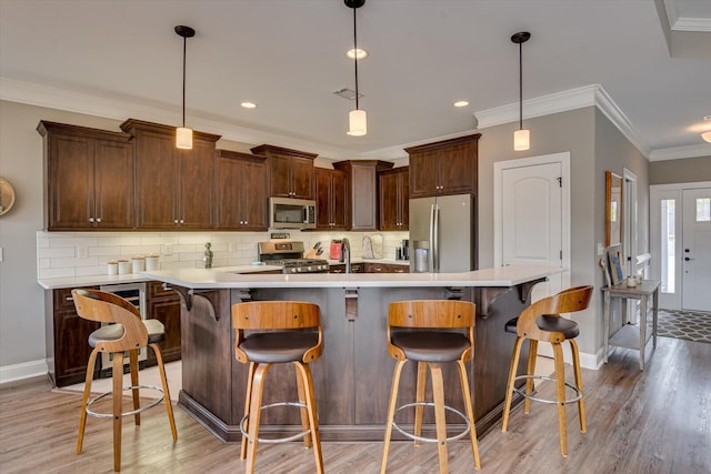 kitchen with crown molding, light wood finished floors, light countertops, backsplash, and appliances with stainless steel finishes