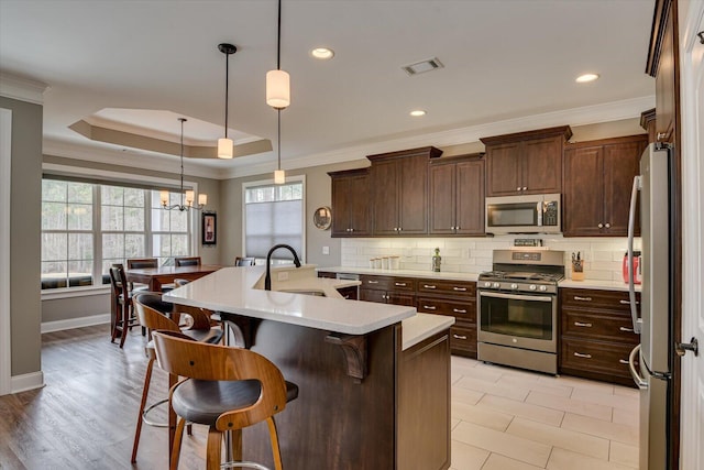 kitchen featuring stainless steel appliances, light countertops, visible vents, decorative backsplash, and ornamental molding