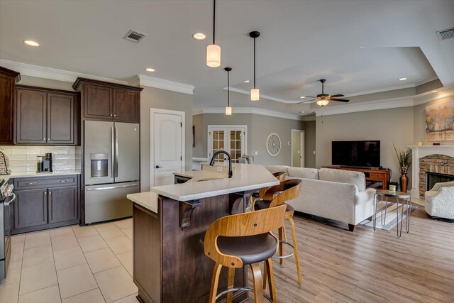 kitchen with stainless steel appliances, a fireplace, a sink, visible vents, and light countertops