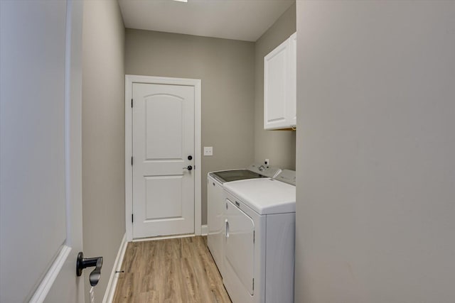 washroom featuring baseboards, cabinet space, washer and clothes dryer, and light wood finished floors