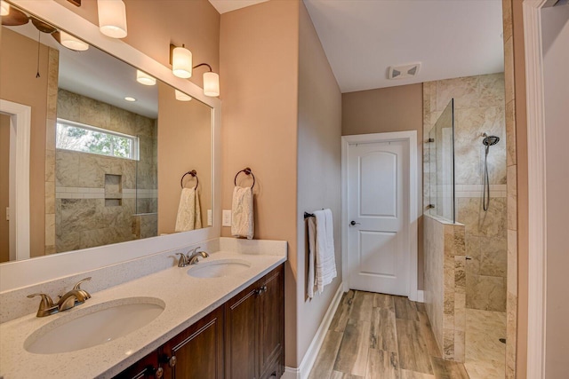 bathroom with double vanity, a sink, and walk in shower