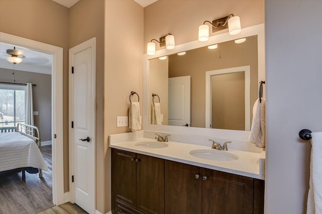 ensuite bathroom with baseboards, a sink, ensuite bath, and double vanity