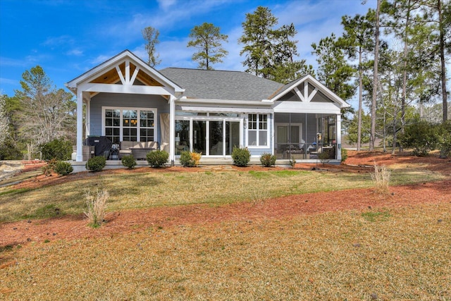 rear view of house featuring a yard, a porch, a shingled roof, and a sunroom