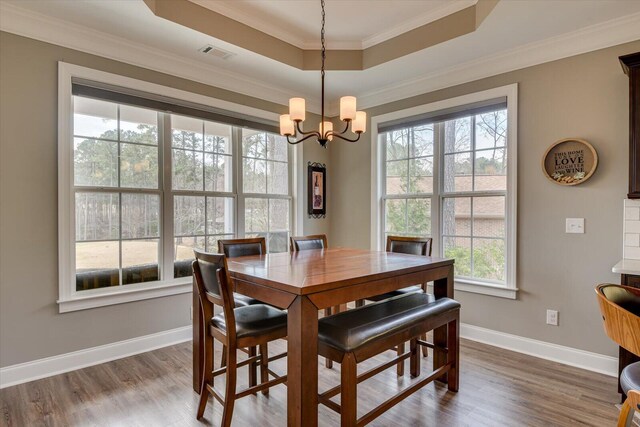 dining area featuring dark wood-style floors, a tray ceiling, and ornamental molding