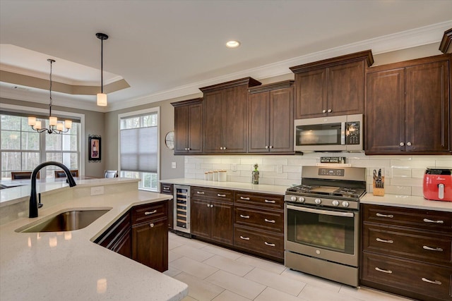 kitchen with beverage cooler, a sink, hanging light fixtures, appliances with stainless steel finishes, and crown molding