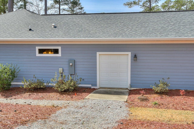 property entrance featuring an attached garage and a shingled roof