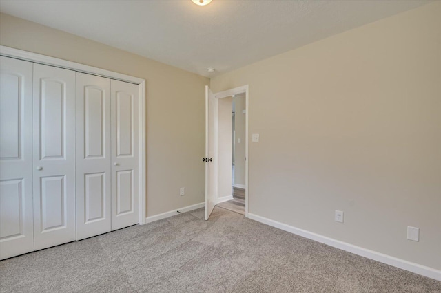 unfurnished bedroom with light colored carpet and a closet