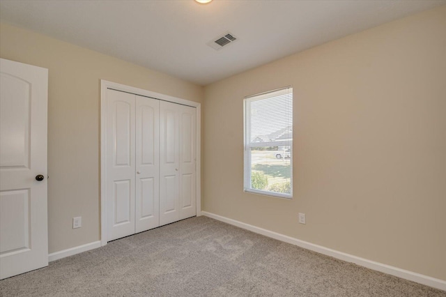 unfurnished bedroom with light colored carpet and a closet