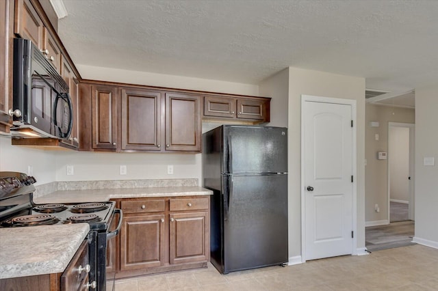 kitchen with black appliances, light tile patterned floors, and a textured ceiling