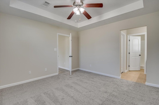 carpeted empty room featuring a tray ceiling and ceiling fan