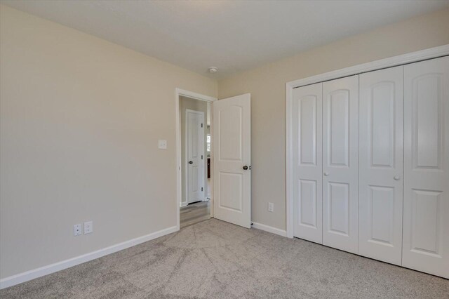 unfurnished bedroom featuring light colored carpet and a closet