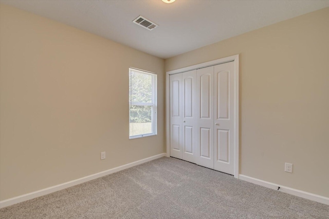 unfurnished bedroom with light carpet and a closet