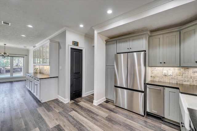 kitchen with hardwood / wood-style flooring, gray cabinetry, stainless steel refrigerator, and decorative backsplash