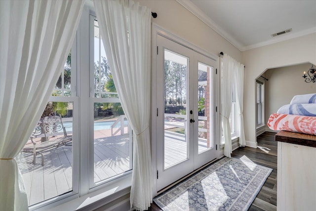 entryway with a wealth of natural light, ornamental molding, and dark hardwood / wood-style floors