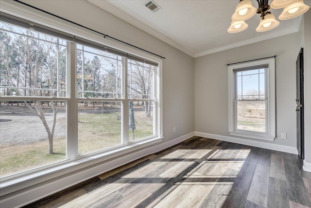 unfurnished dining area with ornamental molding, plenty of natural light, dark hardwood / wood-style floors, and an inviting chandelier