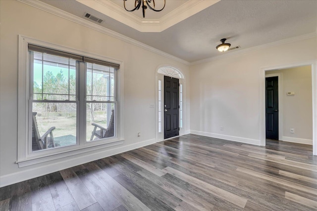 empty room featuring dark hardwood / wood-style flooring, a notable chandelier, and crown molding