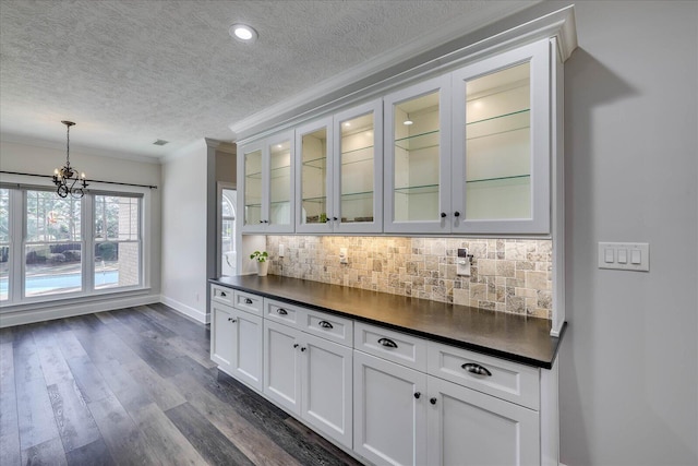 bar featuring white cabinetry, backsplash, dark hardwood / wood-style floors, ornamental molding, and decorative light fixtures