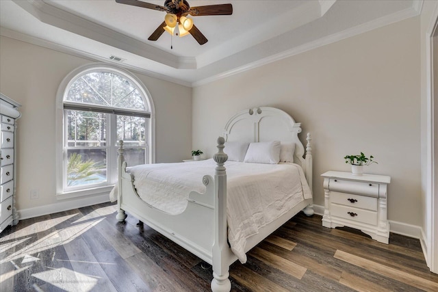 bedroom featuring ornamental molding, dark hardwood / wood-style floors, ceiling fan, and a tray ceiling