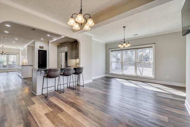 kitchen featuring stainless steel fridge, dark wood-type flooring, a kitchen breakfast bar, and a chandelier