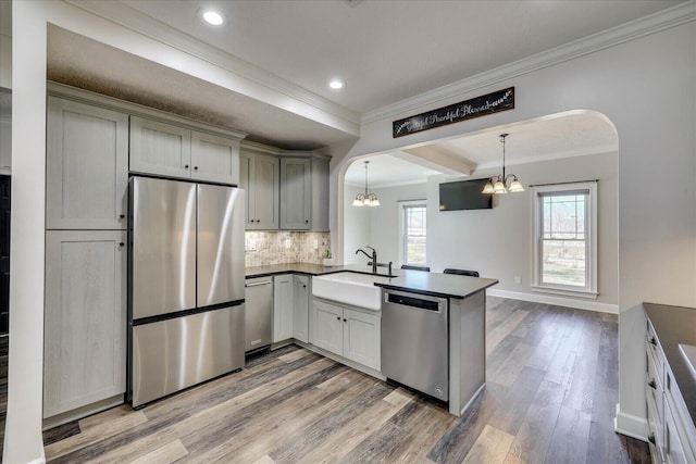 kitchen with sink, appliances with stainless steel finishes, gray cabinetry, decorative light fixtures, and kitchen peninsula