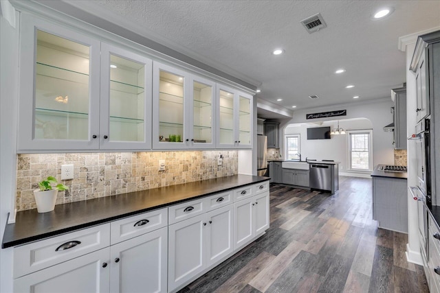 kitchen with crown molding, appliances with stainless steel finishes, decorative light fixtures, and white cabinets