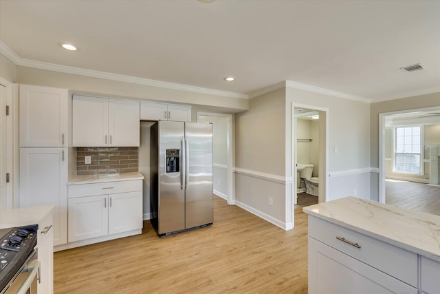 4142 Quinn Dr, Evans, GA 30809 - kitchen featuring stainless steel refrigerator with ice dispenser, stove, backsplash, light wood finished floors, and white cabinetry