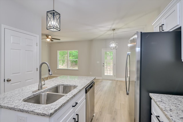 2815 Ridge Crest Dr, Hephzibah, GA 30815 - kitchen with stainless steel appliances, a sink, white cabinetry, light wood finished floors, and decorative light fixtures