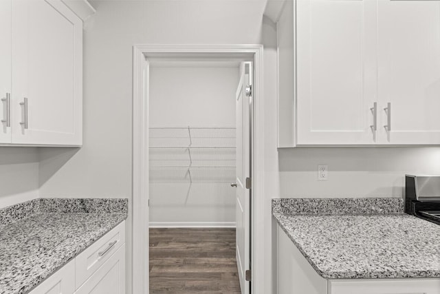 kitchen with white cabinetry, dark wood-type flooring, and light stone counters