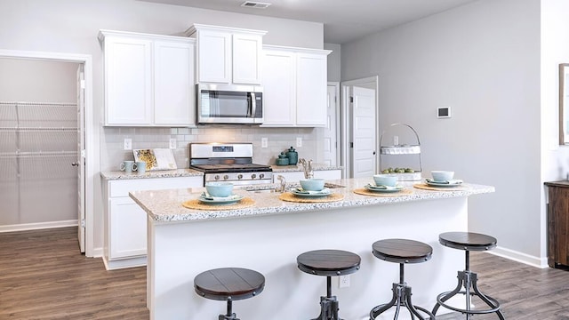 kitchen featuring white cabinetry, appliances with stainless steel finishes, an island with sink, and backsplash