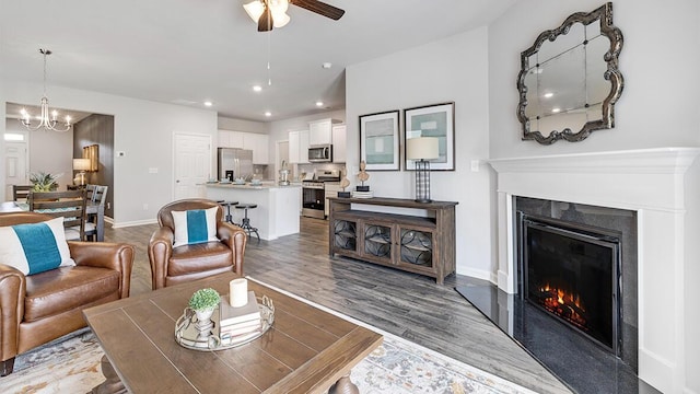 living room with ceiling fan with notable chandelier and hardwood / wood-style floors