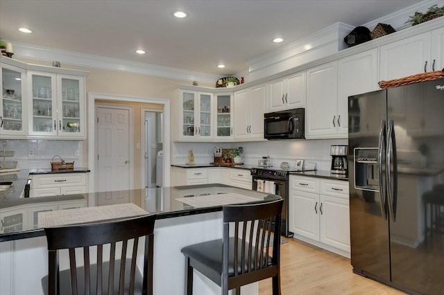 kitchen featuring light hardwood / wood-style flooring, black appliances, tasteful backsplash, white cabinets, and ornamental molding